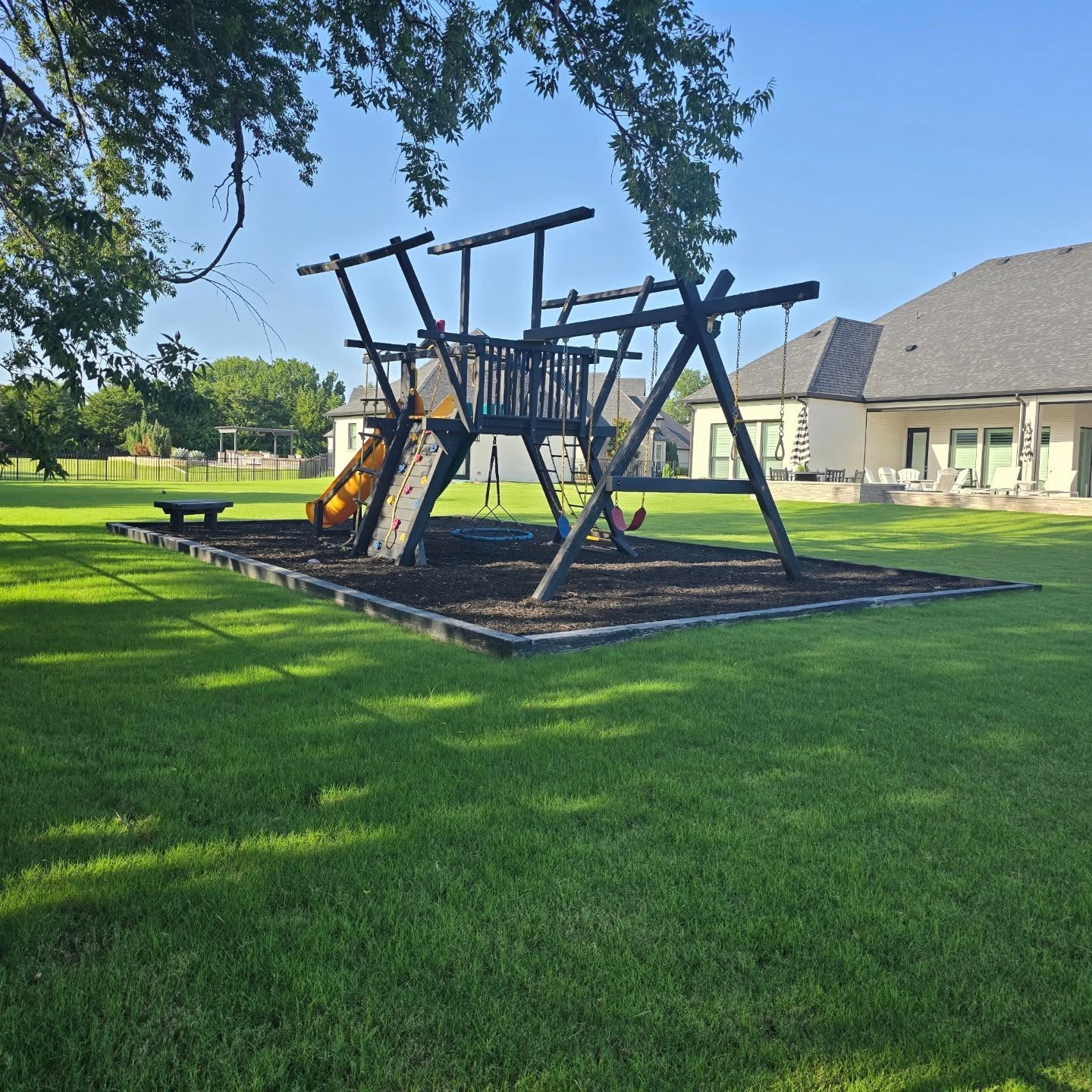 Green backyard lawn with swing set maintained through professional lawn care